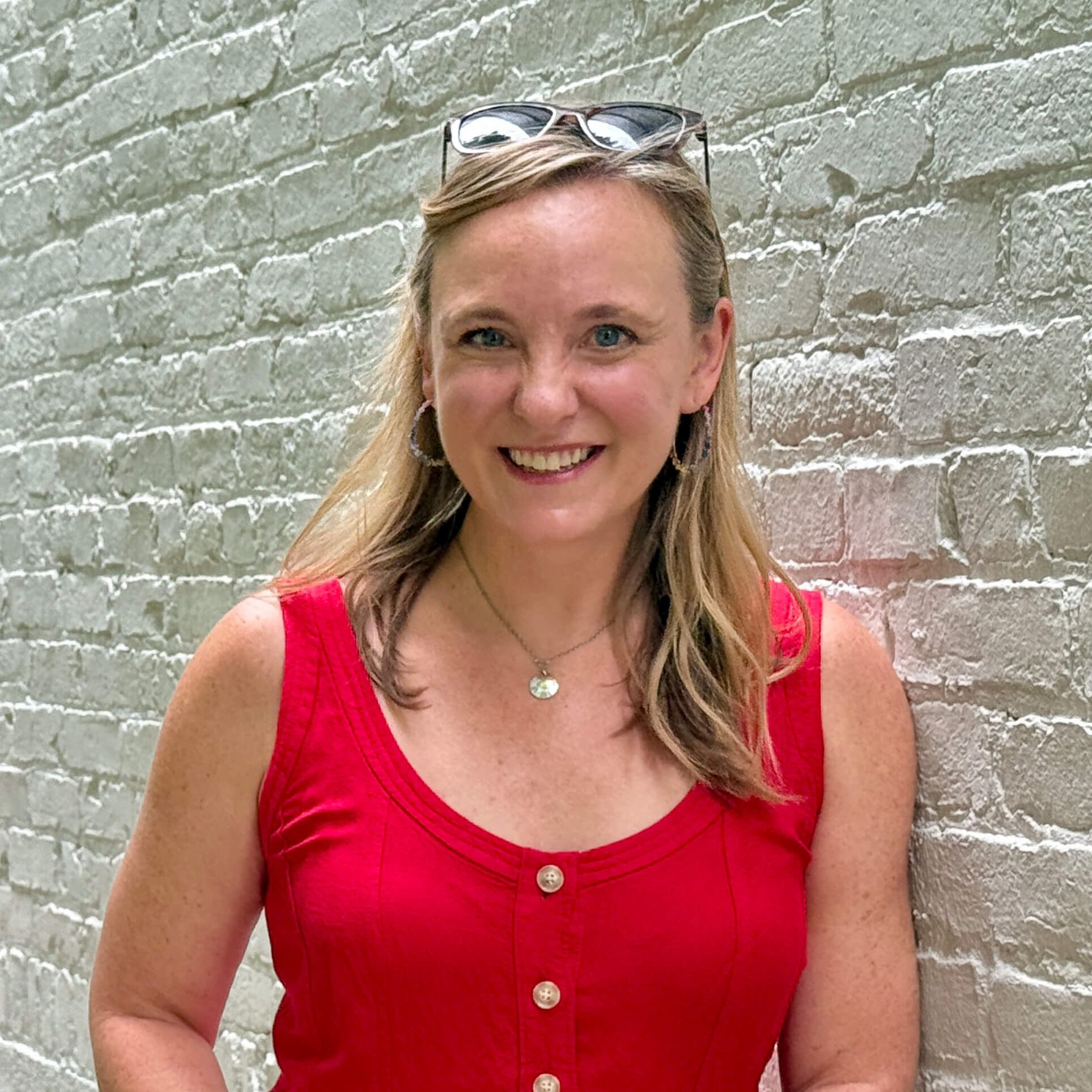 A photo of Dawn in a red shirt leaning against a brick wall